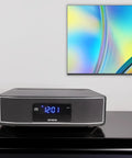 Exos Home Speaker With 30W RMS Power, Bluetooth Streaming, CD Player, and FM Radio on a shelf below a colorful wall art piece.