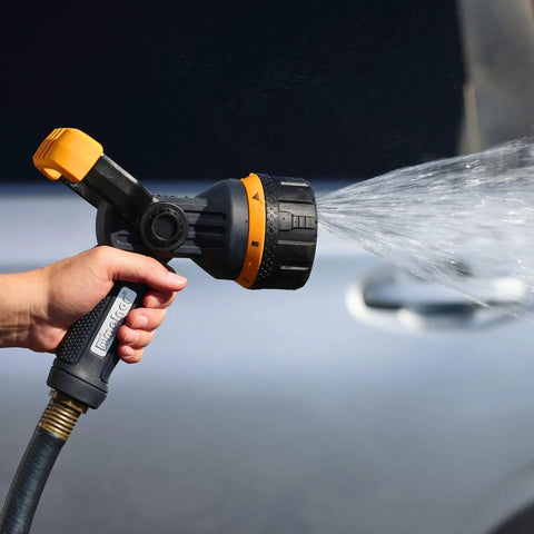 Hand using Torrent Firemans Nozzle with Quick Connect Set for spraying water on a car, showing seven spray patterns.