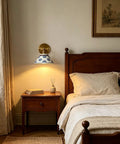 MECOLA Vintage Ceramic Shade Wall Sconce Adjustable Angle Wall Mount Light in a cozy bedroom with vintage wooden furniture.