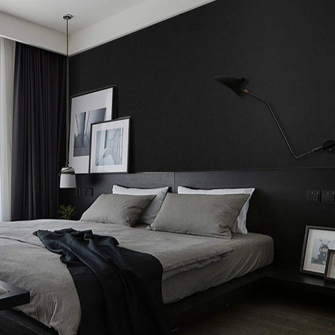 Stylish bedroom with dark wall, modern decor, and framed art above a bed.