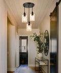 Industrial Three Light Pendant Light With Adjustable Height Up To 34 Inches, Black Finish And Clear Glass Shade installed in hallway