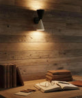 Mid-Century Two-Tone Cone Wall Sconce Light - Black & White Dual Funnel Wall Mounted Lamp with Gold Accent Ring - Up and Down Wall Lighting Fixture for Living Room & Bedroom illuminating a desk with books.