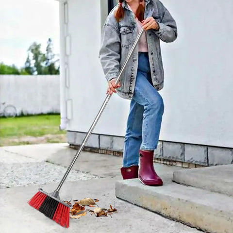 Person using Heavy Duty Long Handle Outdoor Broom 62 Inch For Tough Yard Work And Garage Cleanup to sweep leaves off driveway.