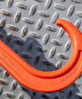 Close-up of red G8 forged hook from Alloy Tow Chain With Forged Long J Hook 3/8 Inch By 8 Foot Grade 80 Pro Series 7,100 Pound Safe Working Load Heavy Duty Tow Chain For Trucks Towing And Vehicle Recovery Ideal For Heavy Duty Towing On Flatbeds And Rural Roads on a textured metal surface.