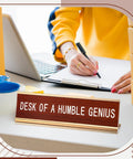Desk Of A Humble Genius Funny Desk Sign With Aluminum Frame And Wood Grain Finish on office desk with laptop and papers