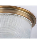 Close-up of vintage brass two light close to ceiling flush mount fixture in Archie collection style with prismatic glass