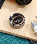 Drill Press Return Spring Set For Quill Coil Assembly with heavy-duty steel spring on a wooden bench, tool at side.
