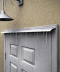 Heavy Duty Exterior Door Rain Drip Guard With Slick White Aluminum Finish installed above a door during heavy rain.