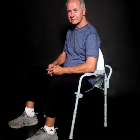 Heavy Duty Toilet Lid Back Support Cushion For Seniors And Postpartum Moms Water Resistant Non Slip Lumbar Pillow To Deliver Major Lower Back Relief During Bathroom Breaks Easy Slip On Design For Oval Or Round Seats Straight Up Comfy with an older man sitting on a lightweight chair.