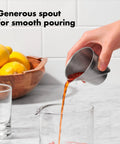 Hand pouring liquid from Stainless Steel Angled Measuring Jigger For Easy Reading From Above With Dual Ounce And Tablespoon Markings