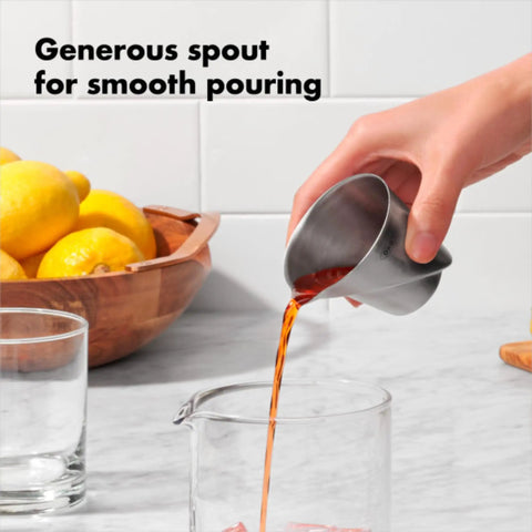 Hand pouring liquid from Stainless Steel Angled Measuring Jigger For Easy Reading From Above With Dual Ounce And Tablespoon Markings