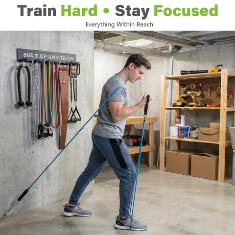 Man using a resistance band with Built Like A Tank Wall Mounted Workout Gear Organizer Rack With Eight Heavy Duty Hooks.