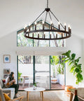 Black Wagon Wheel Chandelier 40 Inch With 20 Lights hanging in modern living room with high ceilings, creating cozy glow.
