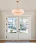 Totally Iconic 24 Inch Linen Drum Chandelier With Six Warm Lights Featuring Sleek Gold Frame And Three Tier Vintage Farmhouse Design hanging above a front door.