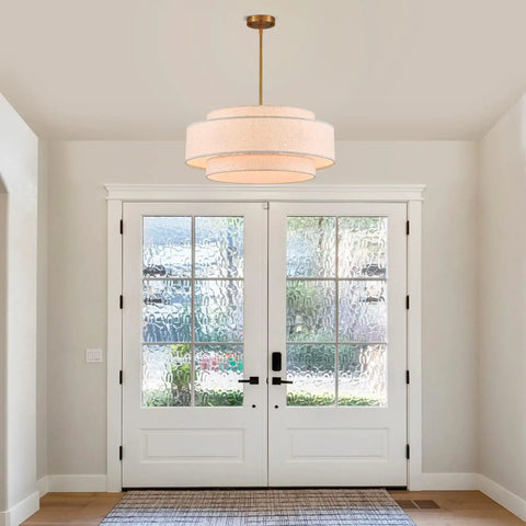 Totally Iconic 24 Inch Linen Drum Chandelier With Six Warm Lights Featuring Sleek Gold Frame And Three Tier Vintage Farmhouse Design hanging above a front door.