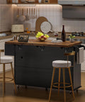60 Inch Kitchen Island With Power Outlet And Drop Leaf in black with wooden top, featuring spice rack and towel holder in cozy kitchen
