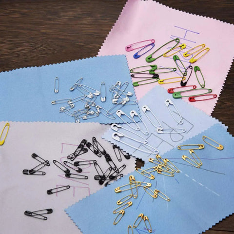 Kickass Assorted Steel Safety Pins Bulk Kit For Sewing Tailoring And Crafting on colored fabric swatches.