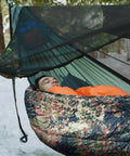 Person sleeping in a hammock with Ultralight 4 Season Hammock Underquilt For Camping And Backpacking Insulated Portable Underquilt.