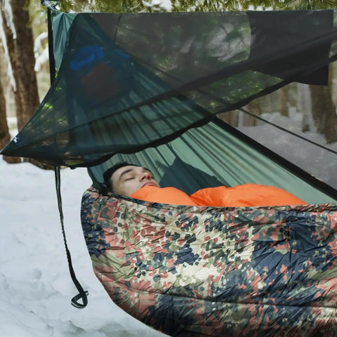 Person sleeping in a hammock with Ultralight 4 Season Hammock Underquilt For Camping And Backpacking Insulated Portable Underquilt.