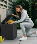 Person using 31 Gallon Barn Style Outdoor Deck Box Waterproof Storage Chest with Lockable Lid, weatherproof resin, black color
