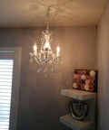 Plug In Crystal Swag Chandelier With Three Lights, White Metal Frame, Clear Glass Stem And Acrylic Crystals, hanging near shelves