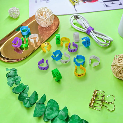 Super Handy Eighty Pack Of Eight Millimeter Numbered Leg Bands In Eight Vibrant Colors Perfect For Identifying Your Quail Pigeon Finch Dove Lovebird And Other Small Birds With Easy Clip On Design displayed on green background with accessories