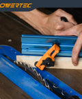 2 Pack Adjustable Mini Hold Down Clamps For T-Track Systems, Boss Level Clamp Action With Multi-Positionable U-Shape Design, Reinforced Plastic Bodies, And 1/4-20 Steel Bolts For Drill Press, Router Table, CNC Machine And More. orange clamp holding wood on blue T-track saw table