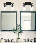 Two Light Matte Black Wall Sconce With Clear Hammered Glass for Modern Bathroom Vanity Wall Lamp for Mirrors Cabinets or Powder Room Up or Down Mount Today, installed above double mirrors in a modern bathroom setting.