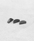 Three metal semi-circular pieces displayed on a textured surface, part of Ten Pack 15x4x6 Mm Woodruff Keys For Lawn Mower Spare Parts.