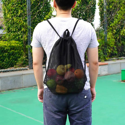 Person wearing black Heavy Duty Mesh Drawstring Gear Bag For Beach, Pool, And Gym Sports Equipment filled with items