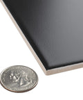 Crown Heights Matte Black Ceramic Wall Tile 3x6 In Glazed With Subtle Texture For Indoor Walls Grade 1 Wall Tile 0.27 In Thick next to a quarter showing size comparison.