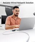 Man using laptop connected with Snagless Short Cat6 Ethernet Cable Set In White 5 Pack 3 Ft Slim Profile 10Gbps Network Patch Cables