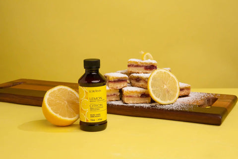 Lemon bakery emulsion bottle with sliced lemon and powdered dessert, part of Bakery Emulsion Variety Pack For Cakes, Cookies And Desserts With Flavors Almond, Butter Vanilla, Lemon, Princess Cake And Cookie, Red Velvet, Strawberry Gluten Free And Keto Friendly, 4 Oz Bottles A Must Have For Home Bakers.