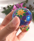 Close-up of a Totally Vintage Enamel Hot Air Balloon Jewelry Box With Rhinestones held in hand, showing colorful pattern