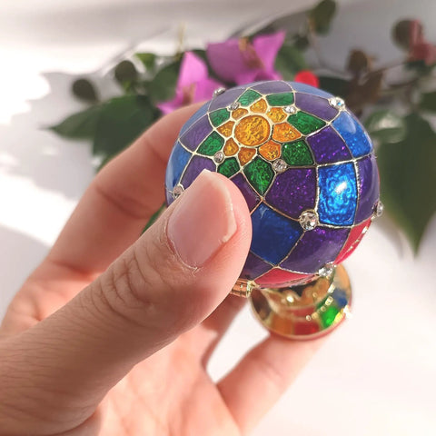 Close-up of a Totally Vintage Enamel Hot Air Balloon Jewelry Box With Rhinestones held in hand, showing colorful pattern