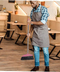 Legit Heavy Duty Pink Broom With Sturdy Steel Handle And Ultra Soft Bristles For Zero Sweat Indoor And Outdoor Floor Cleanup Compact Reusable Dust Brush That Really Cleans in use by a man in an apron.