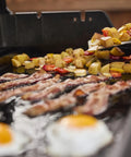 Cooking breakfast on Rust Resistant Outdoor Griddle Insert Full Size Pre Seasoned Carbon Steel Griddle For Searwood And Large Spirit Series Gas Grills Transform Your Grill Into A Flat Top Ready Surface With Even Heat Distribution And Durable Rust Resistant Construction with bacon, eggs, and potatoes.