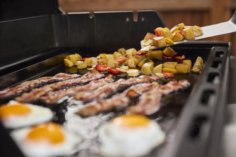 Cooking breakfast on Rust Resistant Outdoor Griddle Insert Full Size Pre Seasoned Carbon Steel Griddle For Searwood And Large Spirit Series Gas Grills Transform Your Grill Into A Flat Top Ready Surface With Even Heat Distribution And Durable Rust Resistant Construction with bacon, eggs, and potatoes.