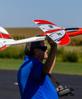Person holding ElectroStreak 1.1m RC Airplane BNF Basic Ready To Fly, Crazy Fast Sport Model with 3S and 4S power on tarmac.