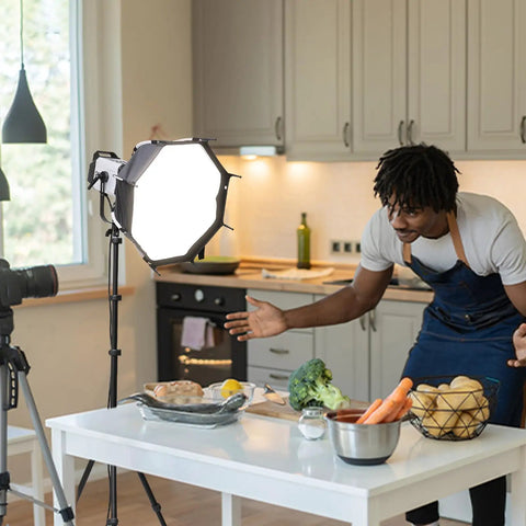 Photographer using Extendable 6.23ft Aluminum Light Stand For Photography with softbox in kitchen studio setup, tripod visible.