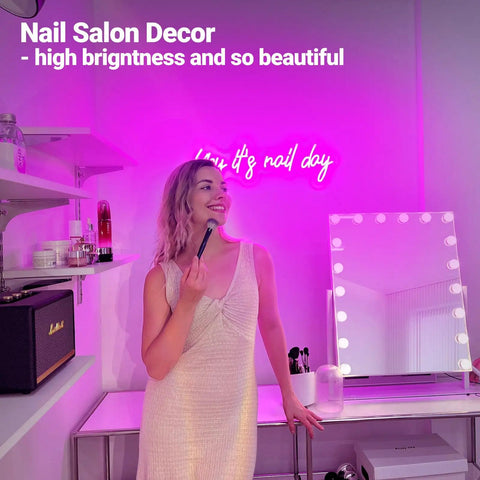 Woman using makeup in beauty studio with Pink Neon Nail Sign For Nail Salon And Beauty Studio Decor LED Light Open Sign Wall Art Perfect For Nail Rooms, Beauty Bars, Spas, Shops, And Home Makeovers, Party Ready For Parties, Weddings, And Social Media Photo Ops glowing in the background.