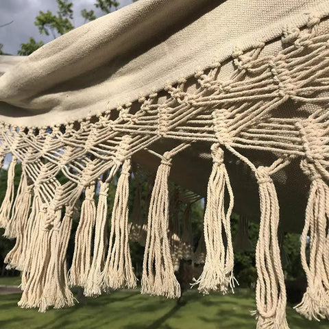 Close-up of crochet fringe on handmade cotton woven hammock chair with rope swing for indoor outdoor patio boho vibes