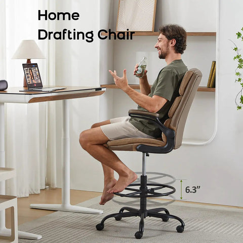 Man seated on Tall Drafting Chair With Padded Flip Up Armrests, Ergonomic Leather Backrest, And Adjustable Footrest Ring For Standing Desks, Tan