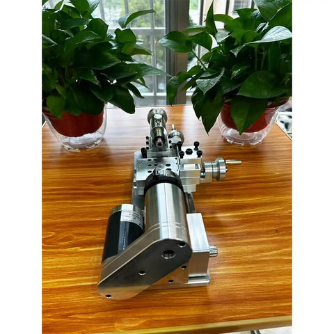Compact Mini Metal Lathe For Benchtop Use With 3 Jaw Chuck And Tailstock on a wooden table with plants in background.