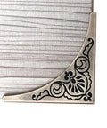 Antique Bronze Metal 4 Pack Corner Protectors Furniture Edge Guards With Classic Carved Details close-up view on wooden table corner.