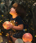 Child holding Lit Galaxy Moon Night Light With Stand And Remote, 3D Printed Moon Lamp In 16 Colors, kid safe