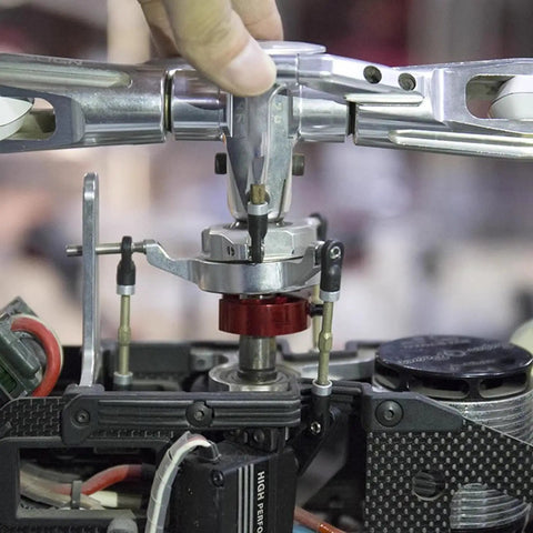 Hands using a Helicopter Swashplate Leveler for 380 470 600 700 models to calibrate swashplate in a model aircraft setup.