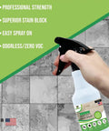 Hand holding spray bottle of Pro Grade Grout Sealer With Odorless Zero VOC Breathe Easy Stain Block Tech against tiled wall.