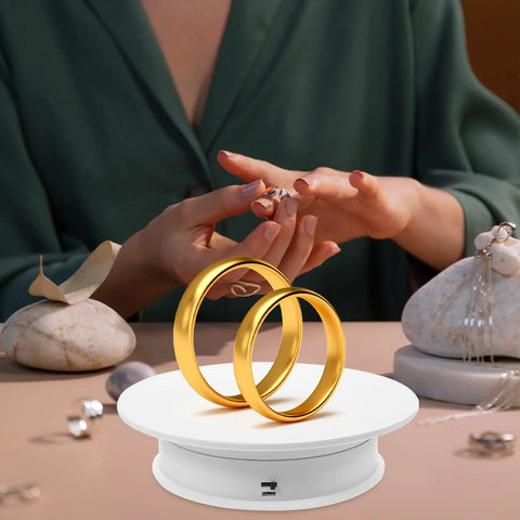 Awesome Electric Rotating Display Stand For Jewelry And Collectibles Featuring 360 Swivel Showcase with two gold rings on white velvet base and hands adjusting rings.