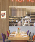 Ramen Club Metal Tin Sign 8x12 Inch Vintage Wall Decor mounted on a restaurant wall, visible alongside a long dining table.
